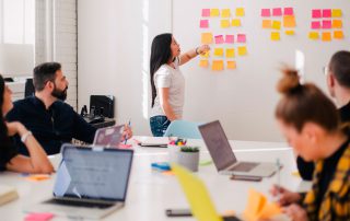 Senhora apresenta ideia com imensos post-it colados numa parede