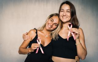 Duas senhoras com laços cor-de-rosa nas mãos