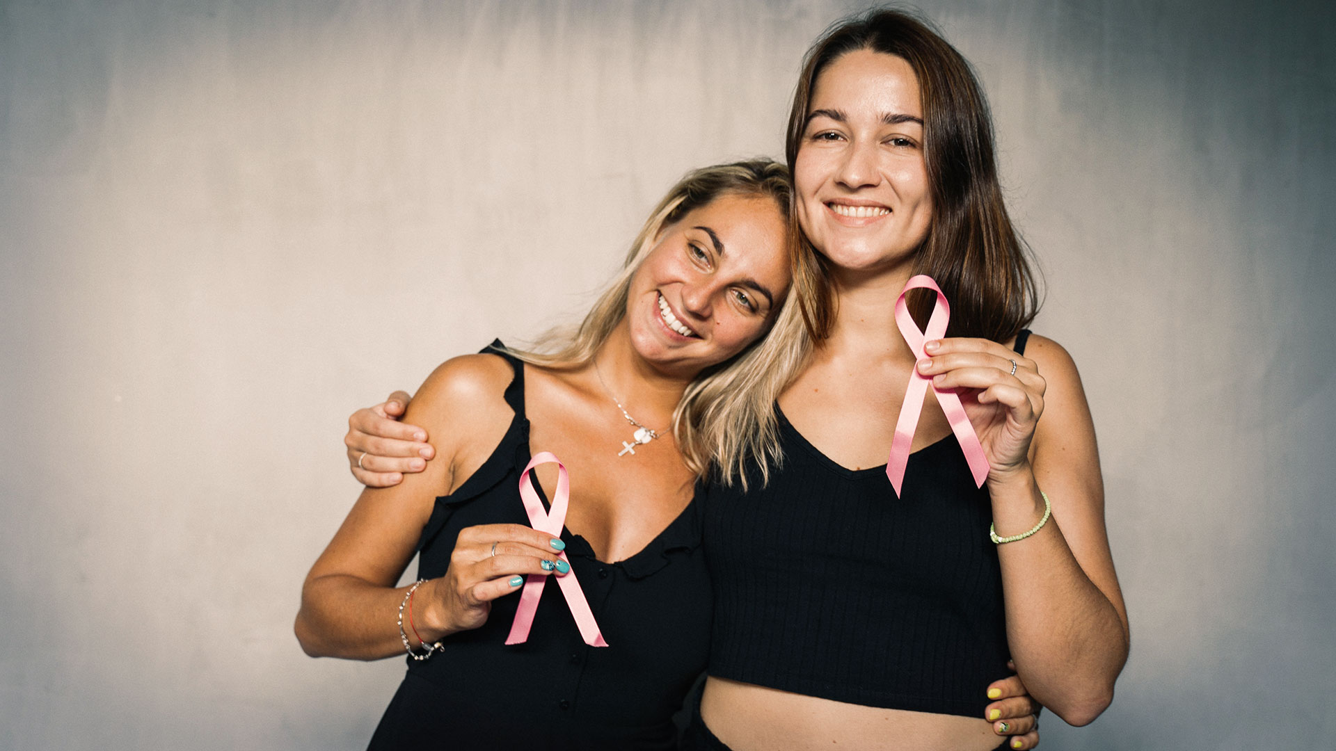 Duas senhoras com laços cor-de-rosa nas mãos