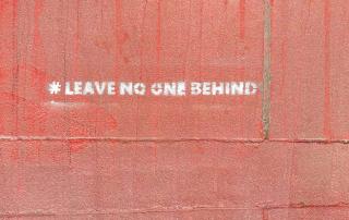 frase "leave no one behind" escrita em parede