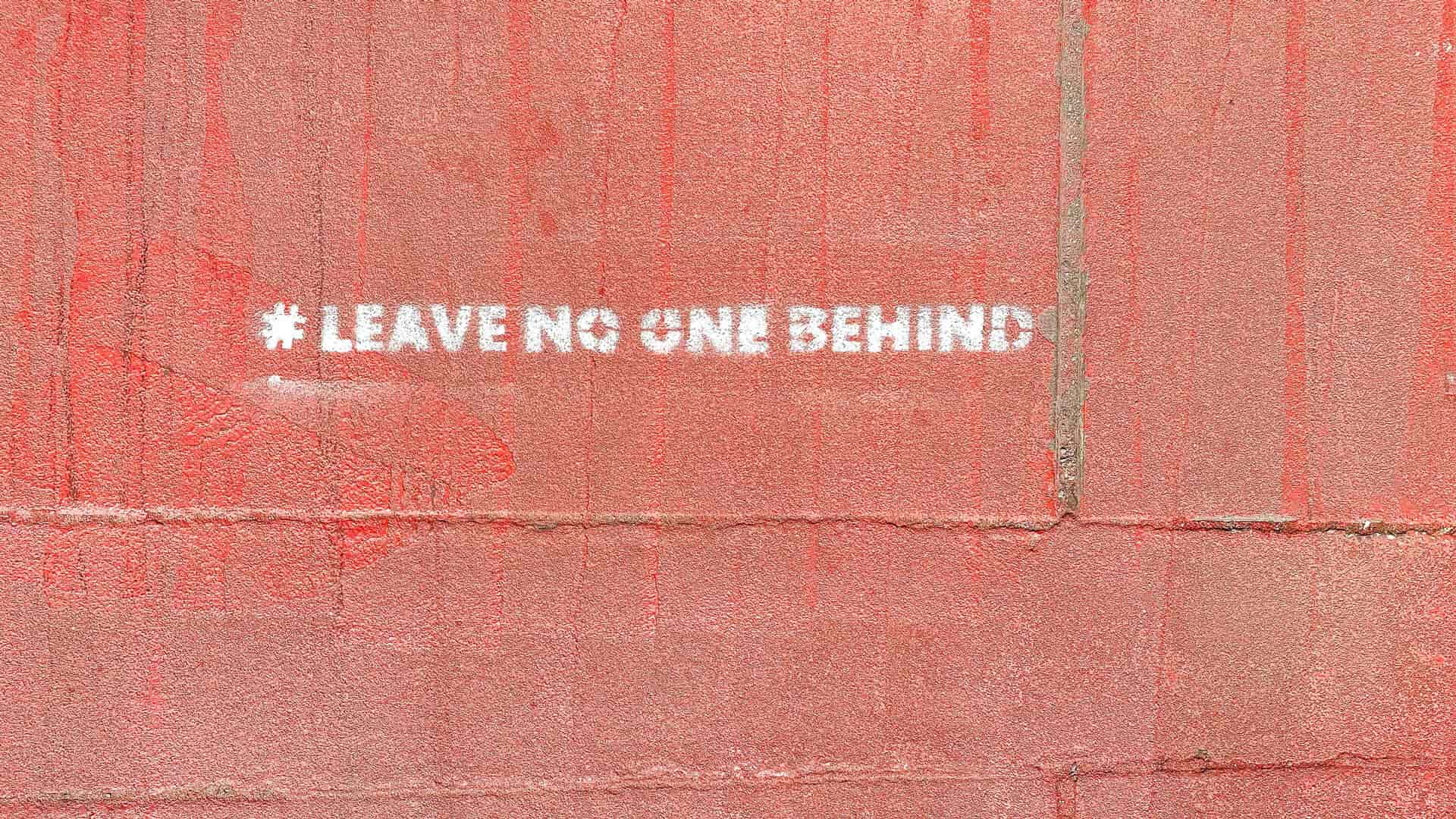 frase "leave no one behind" escrita em parede