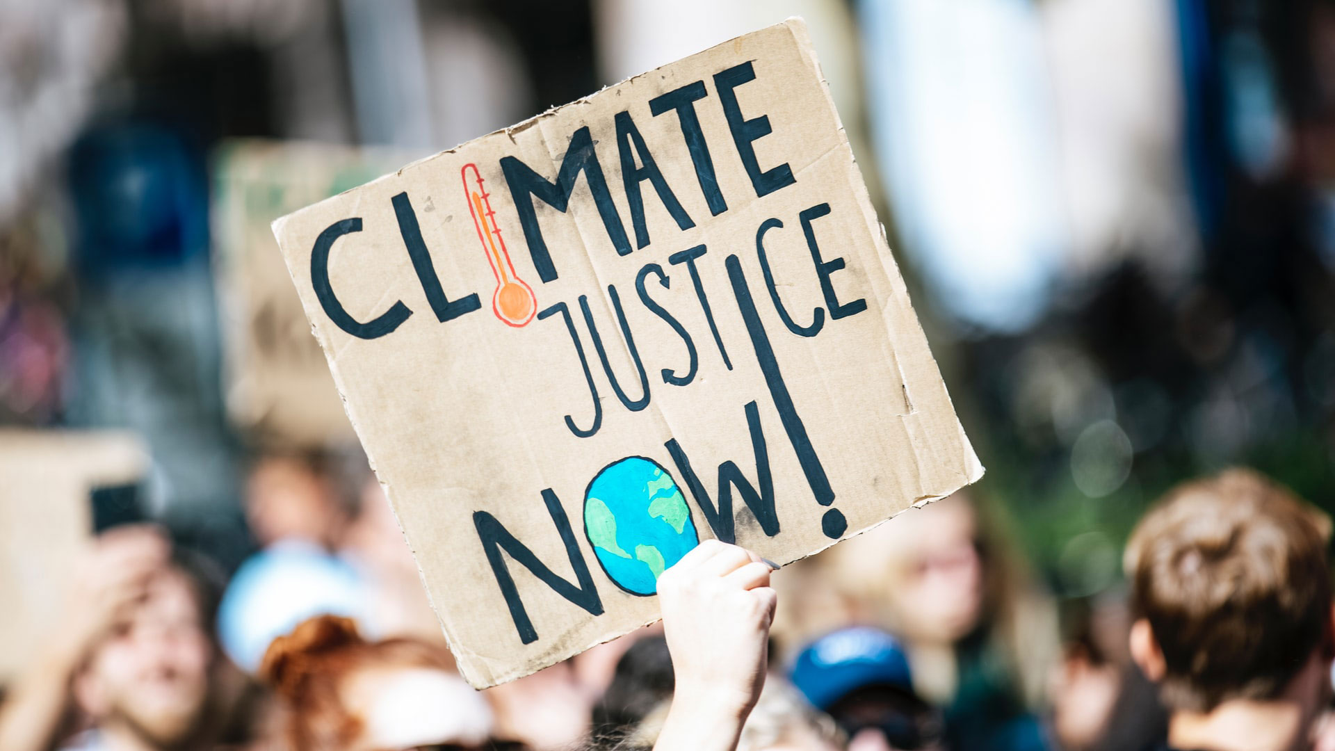 mão empunha cartaz com as palavras "climate justice now!"