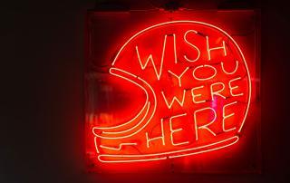 Sinal de neon com as palavras "Wish you were here"