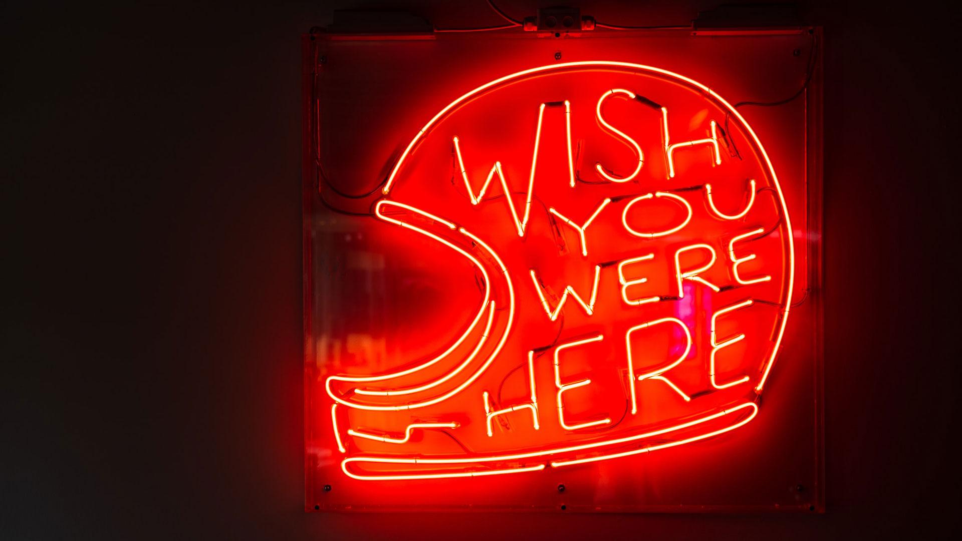 Sinal de neon com as palavras "Wish you were here"
