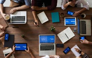 várias pessoas sentadas em mesa de trabalho com computadores