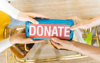 várias mãos seguram caixa de ovos com a palavra "DONATE"
