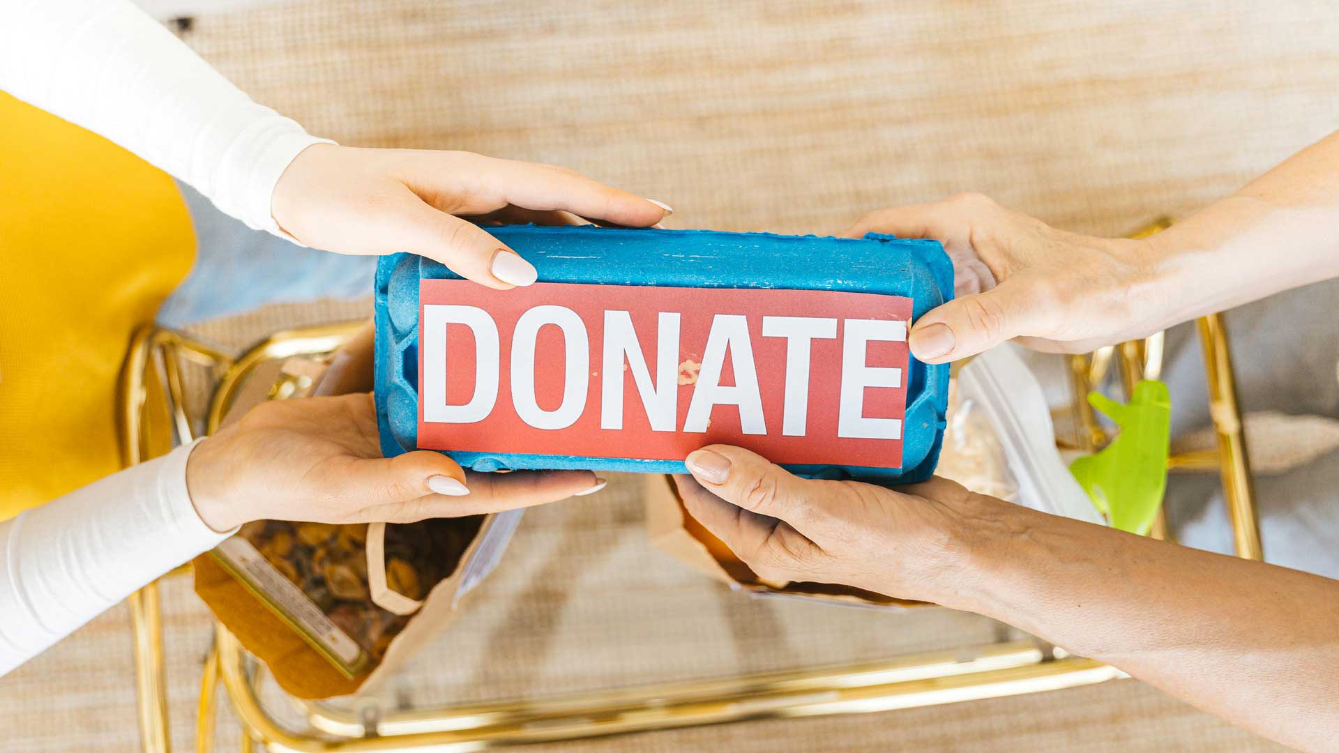 várias mãos seguram caixa de ovos com a palavra "DONATE"